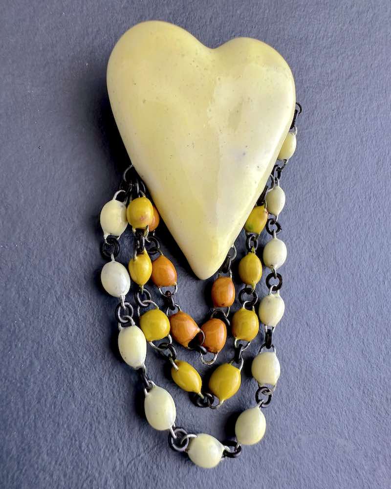 Superbe broche en céramique formée d'un gros coeur jaune pale et trois rangs de perles en 3 jaunes dégradés. Fait main en France