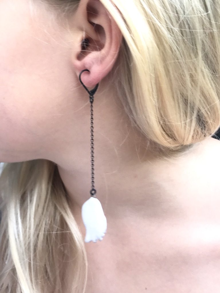 Boucles d'oreilles formées d'une aile en céramique blanche suspendue à une longue chaine, par Claire Hecquet-Chaut