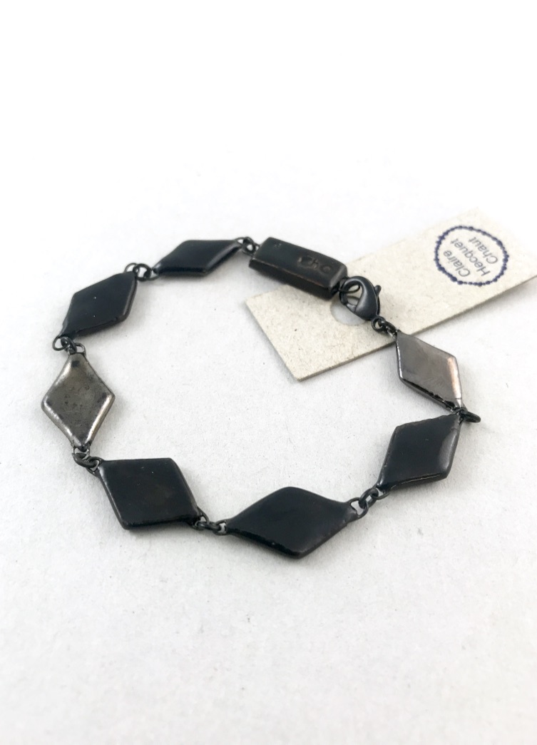Bracelet sobre et chic formé de losanges noir et platine en céramique liés les uns aux autres.