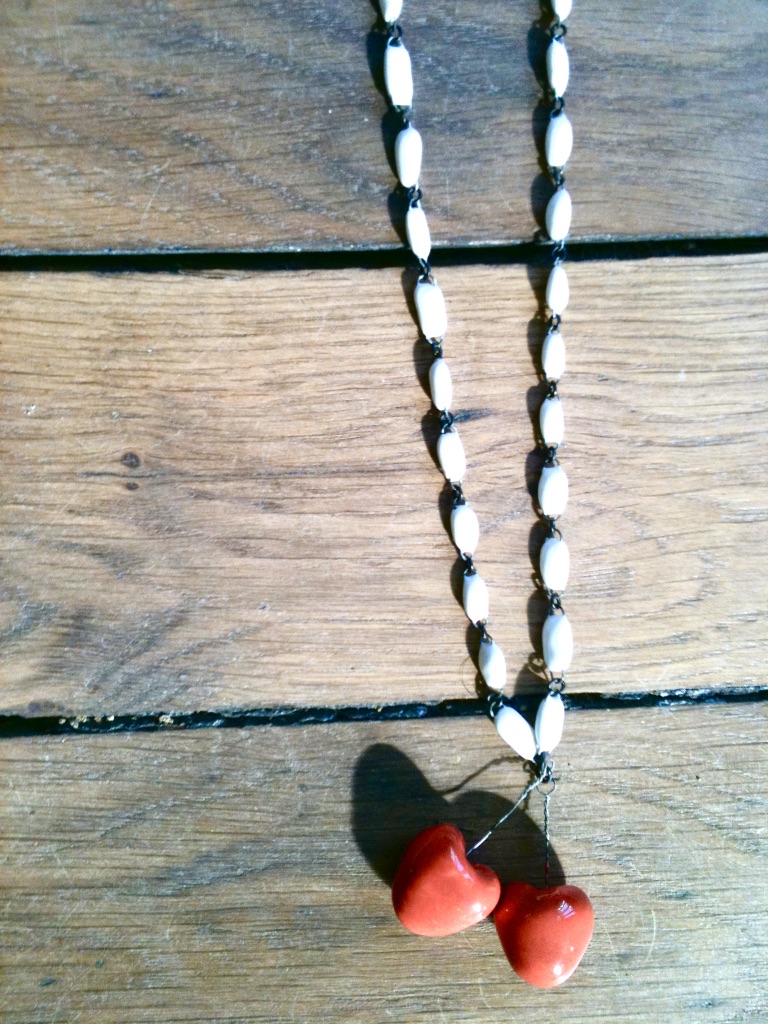 Sautoir long simple et chic formé de perles en céramique noires ou blanches et de deux cerises or ou rouge, fait main en France par Claire Hecquet-Chaut