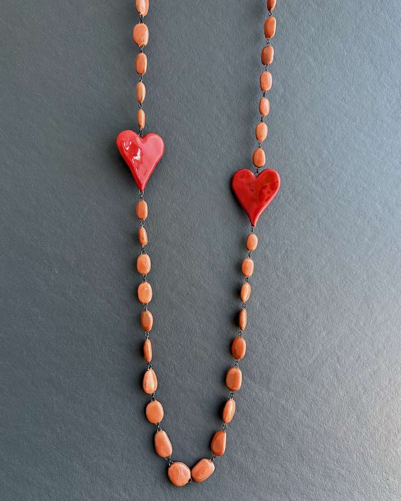 Collier inédit formé de perles galet en céramique fait main et ponctué de deux coeurs situé de chaque coté du sautoir