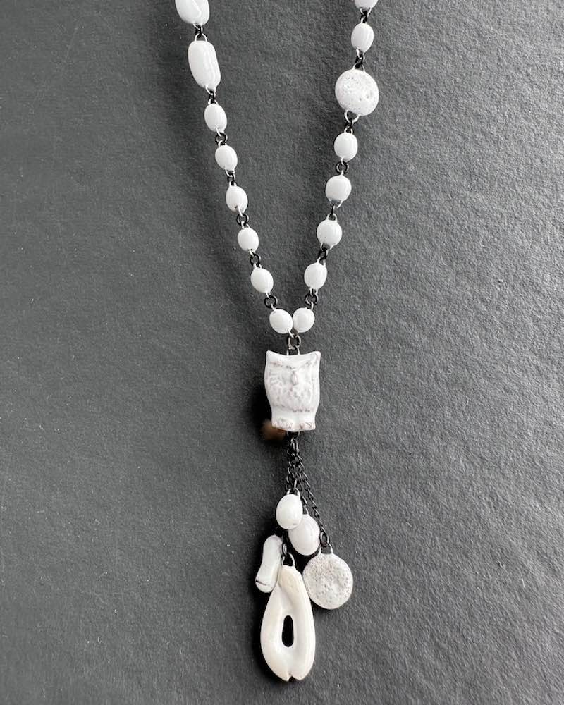 Sautoir mi long en perles de céramique blanches, constitué d'une mini chouette en céramique avec pampilles suspendues à son extrémité , pièce fait main signée claire Hecquet Chaut