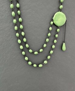 Ras du cou délicat formé de deux lignes de très fines perles en céramique artisanale réunies par une large pastille plate d'un coté a laquelle est suspendue une pampille