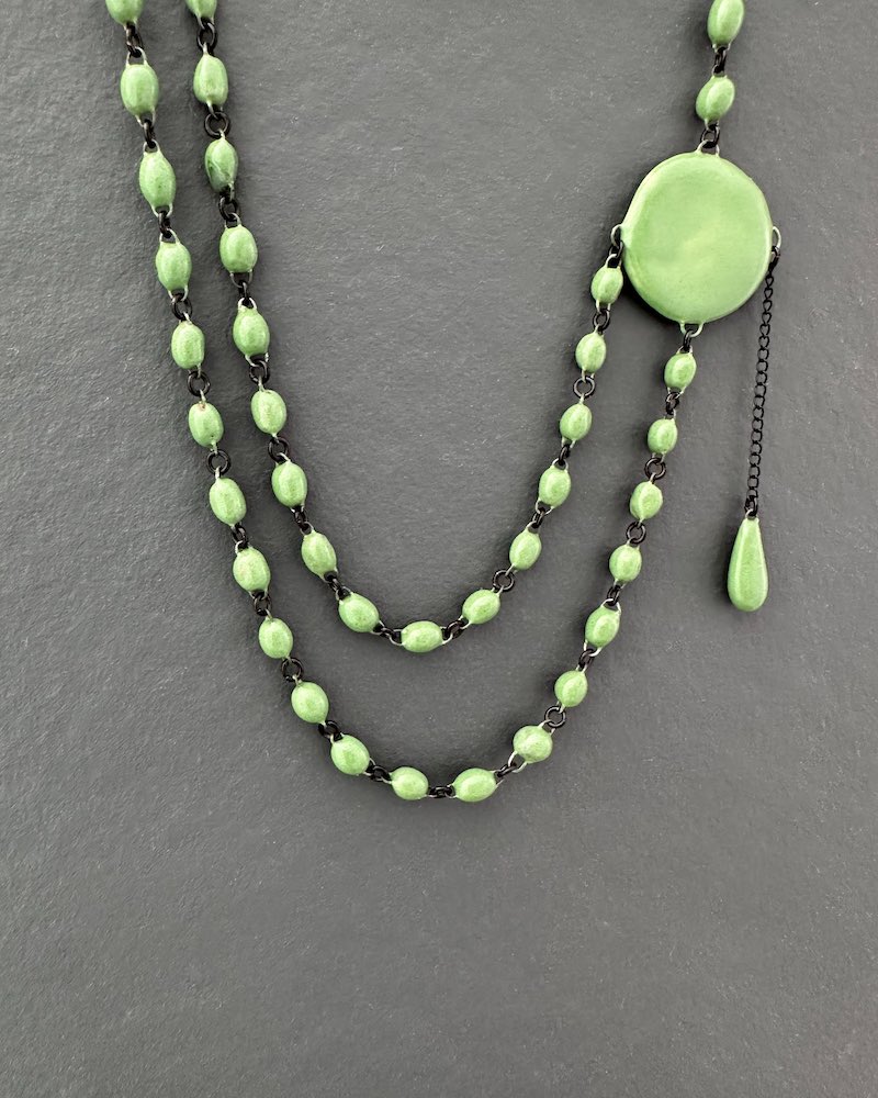 Ras du cou délicat formé de deux lignes de très fines perles en céramique artisanale réunies par une large pastille plate d'un coté a laquelle est suspendue une pampille